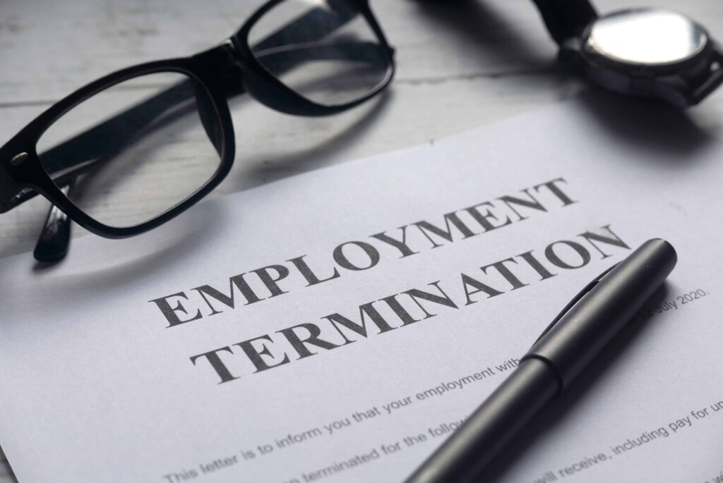 Employment termination contract on a desk with black glasses on top and a black pen