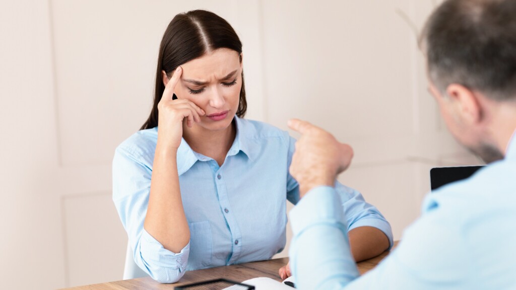 Stressed employee looks upset in workplace meeting